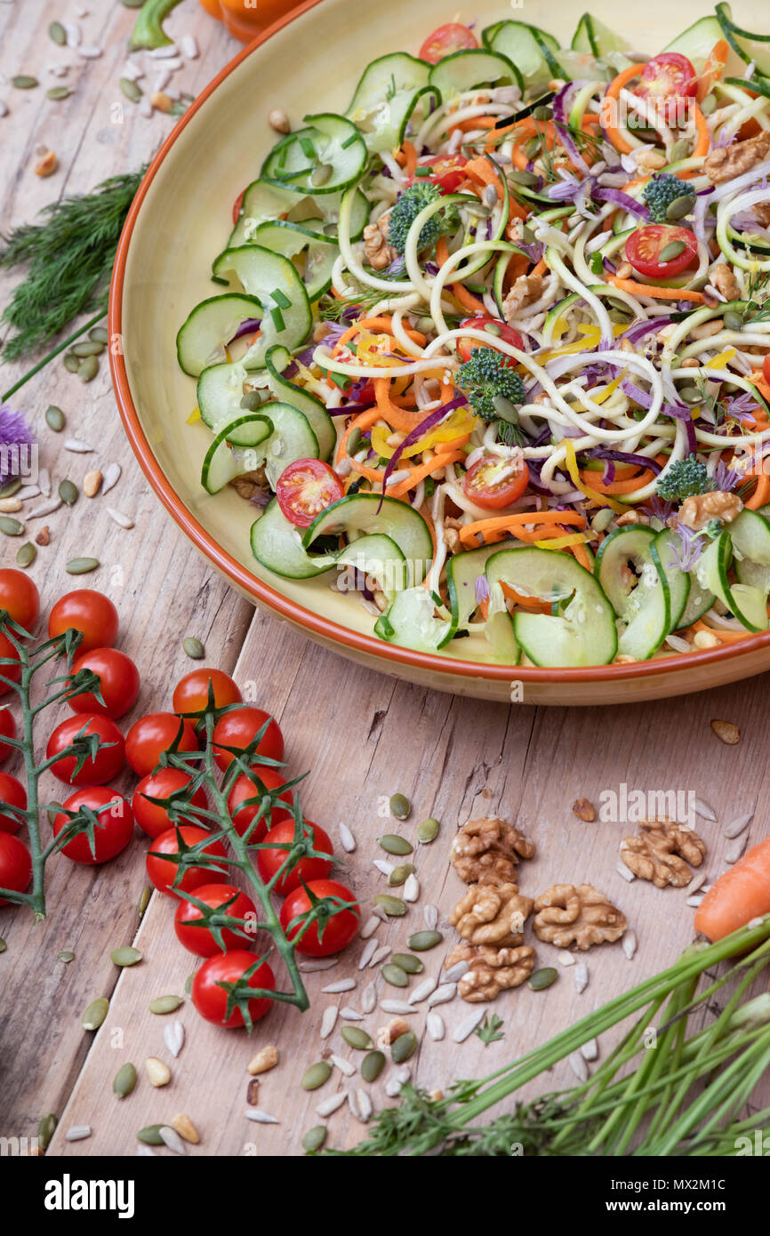 Salade de légumes renforts spiralés dans une cuvette entourée de légumes sur bois Banque D'Images