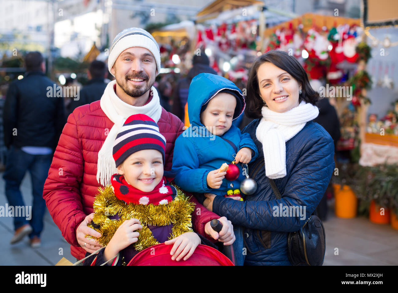 Famille heureuse de quatre au comptoir avec les cadeaux de Noël au marché de Noël Banque D'Images