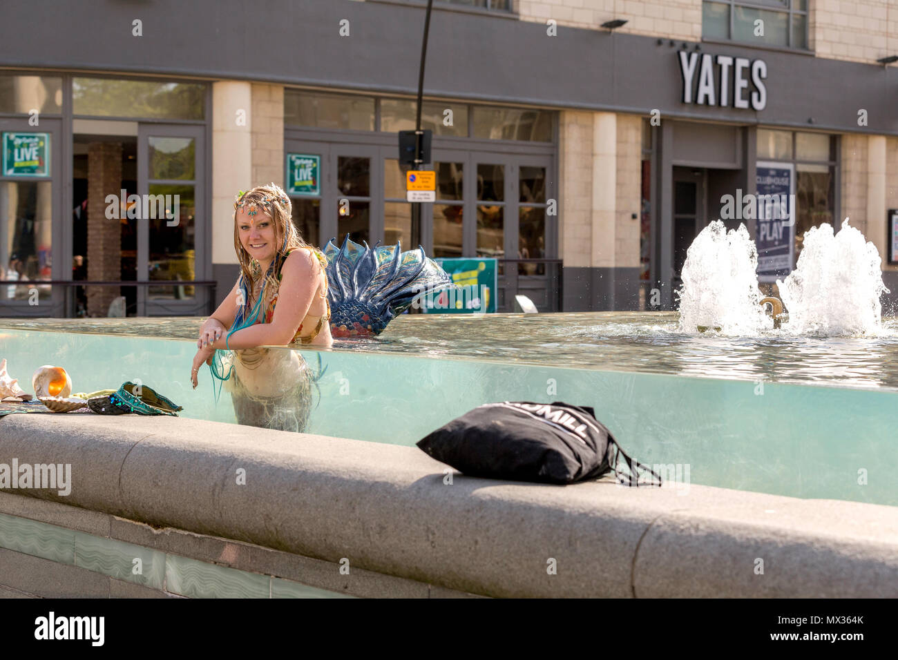 Une femme vêtue d'un costume de sirène pose en restant assis dans une fontaine publique. Sheffield, South Yorkshire, UK. Banque D'Images