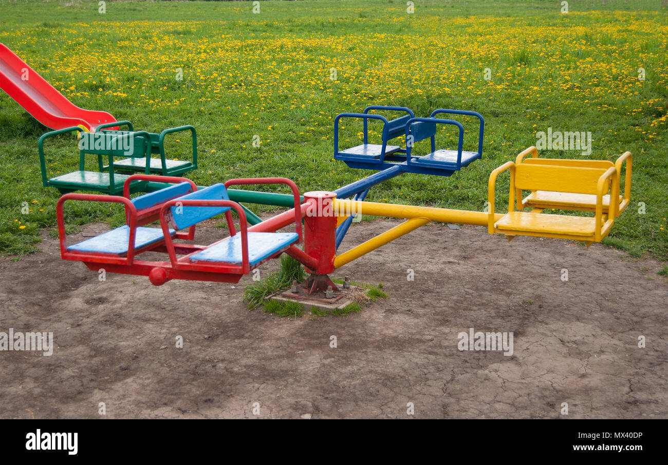 Carrousel pour enfants en quatre endroits, colorées sur un fond d'herbe verte avec pissenlits jaunes Banque D'Images