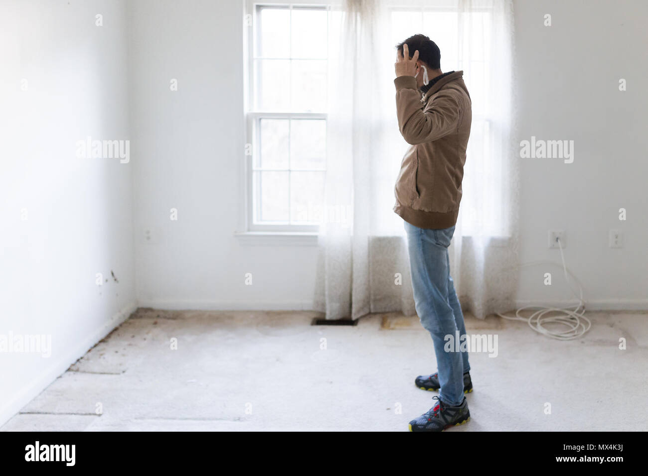 Masque de jeune homme dans l'article à un mur de la salle à la moquette au sol, murs peints en blanc, au cours de la rénovation rénovation, le nettoyage, l'inspection de la saleté Banque D'Images