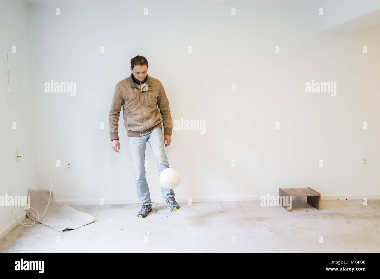 Jeune homme des qualifiés tour avec ballon de soccer jeu sport l'intérieur de sous-sol sale chambre à chambre, vide les taches, vieux tapis Banque D'Images