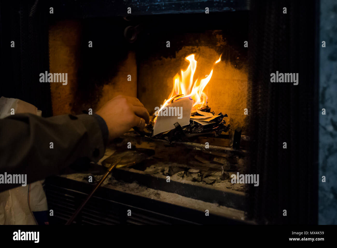 La main de l'homme d'atteindre à l'intérieur papier gravure home intérieur avec cheminée ancienne rétro vintage golden instruments or outils, tels que pelle, frêne Banque D'Images