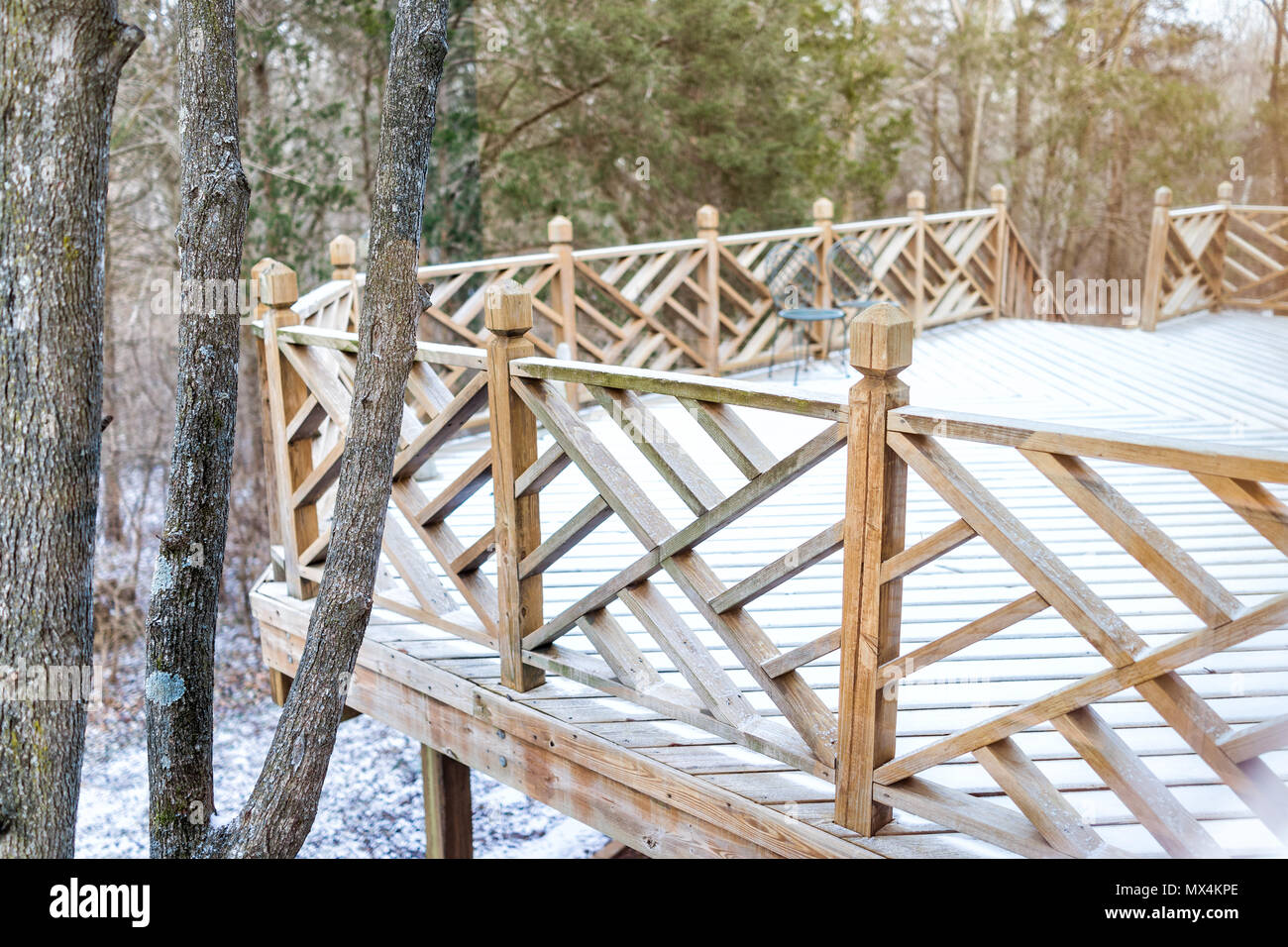 Gros plan du pont en bois vides de la maison avec des chaises, arbres, forêt, décorations sur cour dans quartier avec plancher de bois couvertes de neige au cours de blizzard Banque D'Images