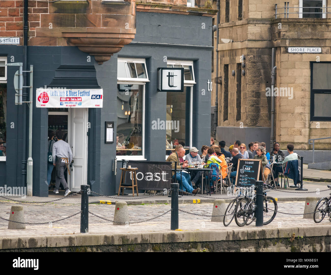Leith Jazz & Blues Festival de musique live dans les restaurants et bars par l'eau de Leith, 3e juin 2018. La Rive, Leith, Edinburgh, Ecosse, Royaume-Uni. Le Jazz and Blues Festival se déroule sur 3 jours de semaine. Les gens envahissent la chaussée extérieure tables des restaurants et bars au bord de l'eau de Leith bénéficiant d'écouter de la musique en direct gratuit. Les gens au bar à vin et restaurant, le toast avec le festival affiche bannière Banque D'Images