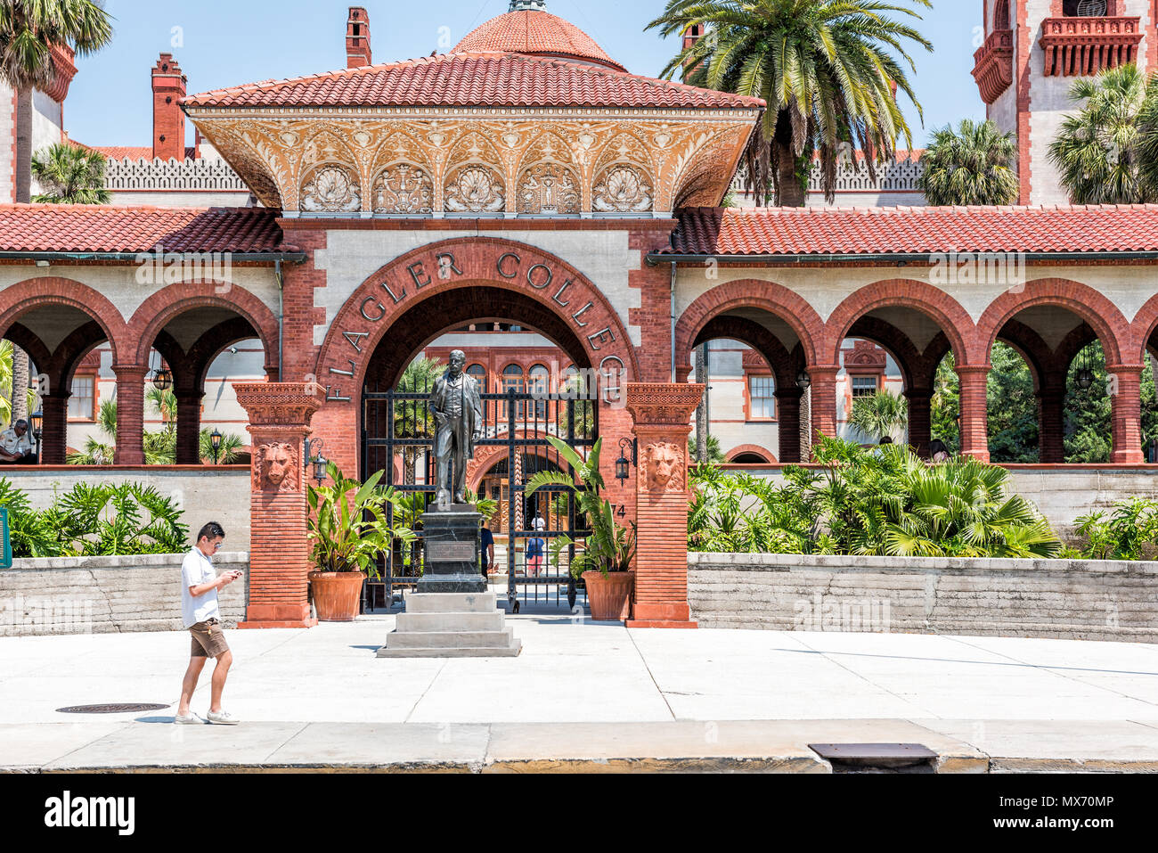 Saint Augustin, USA - 10 mai 2018 : Flagler College avec homme étudiant visiteur touristique billet personne marchant par Florida architecture, célèbre statue en hi Banque D'Images