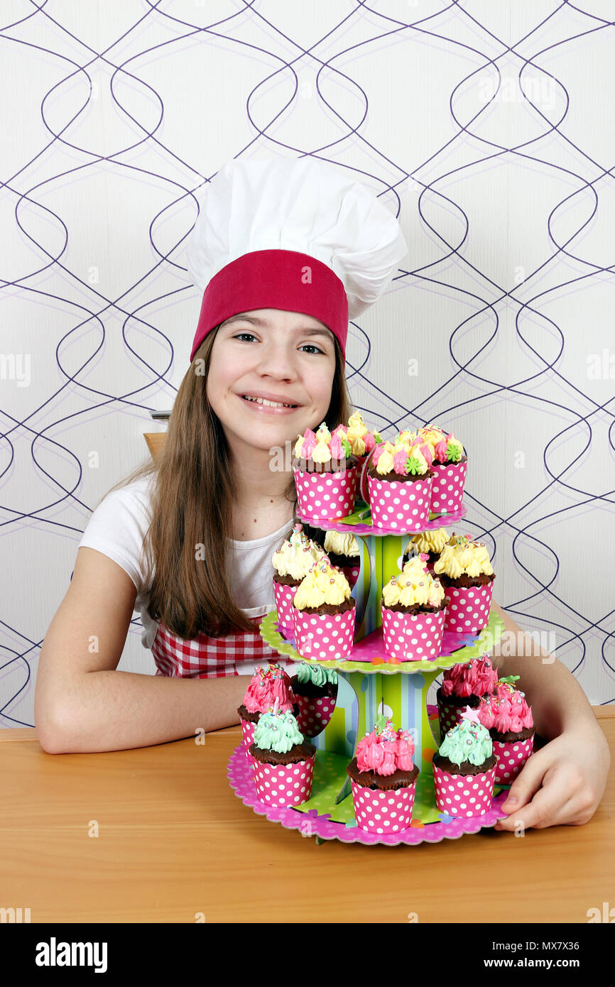 Happy little girl cook avec muffins sur la table Banque D'Images