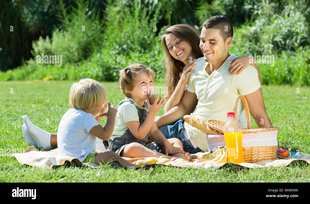 Famille de quatre joyeux pique-nique dans le parc, au jour d'été. Se concentrer sur la fille Banque D'Images