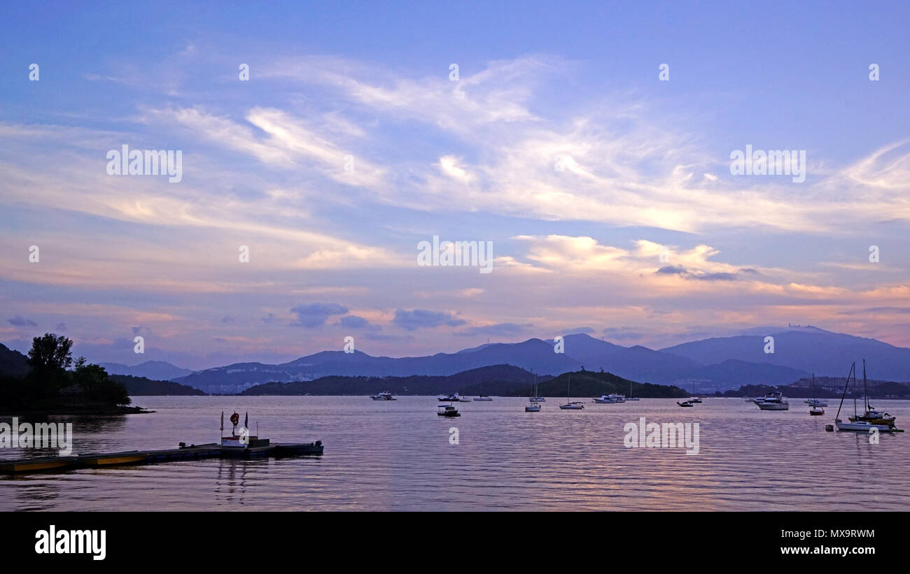 Pier, yacht, voiliers, montagnes, nuages et ciel dégradé magnifique au coucher du soleil Banque D'Images