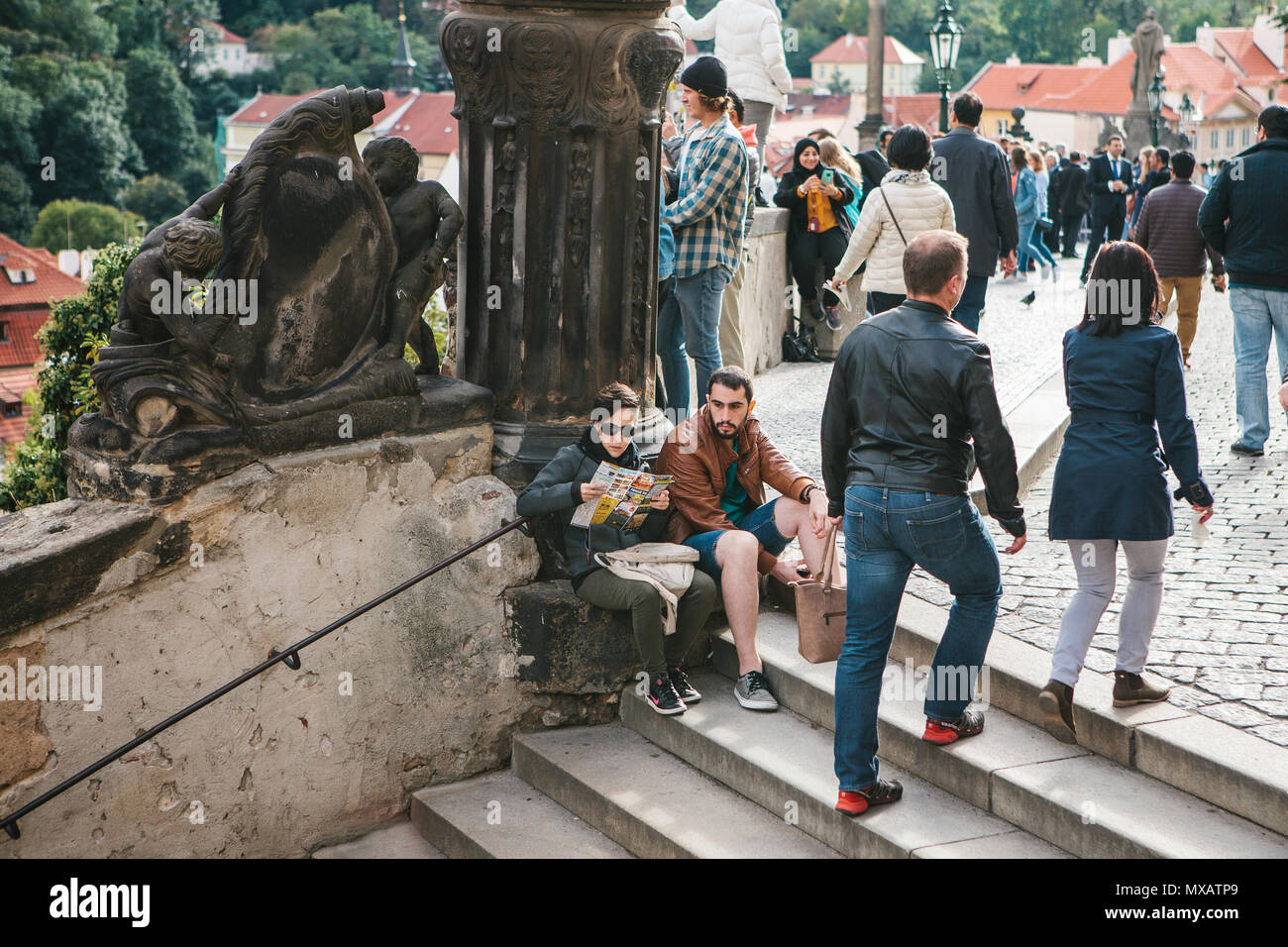 Prague, le 18 septembre 2017 : l'homme et la femme ou les touristes s'asseoir sur l'escalier et se détendre. D'autres personnes sont engagées dans les activités quotidiennes. Banque D'Images