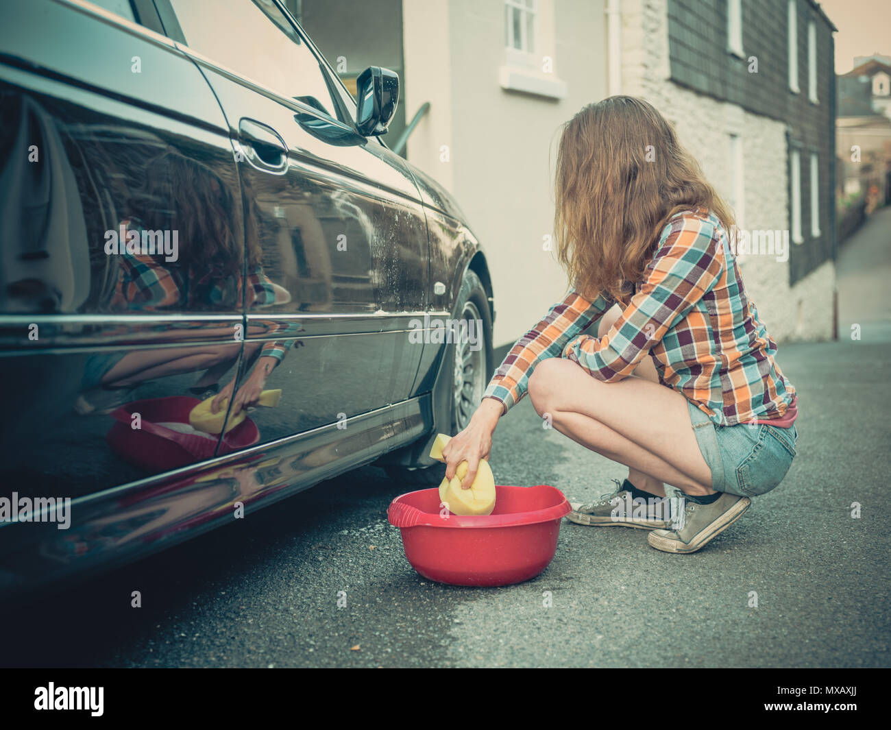 Une jeune femme est savonnage et laver sa voiture Banque D'Images
