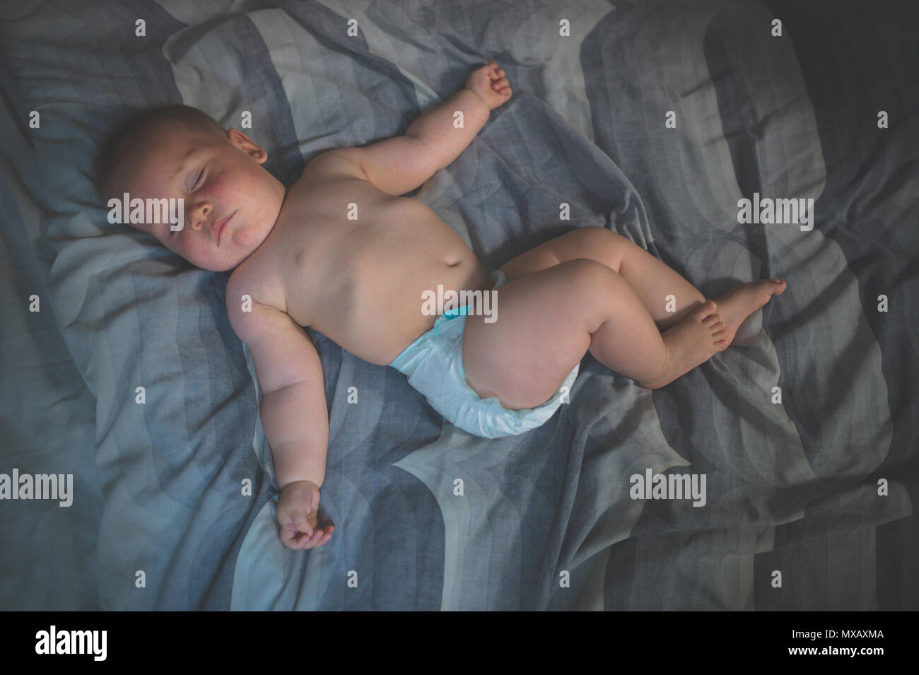 Un mignon petit bébé dans sa couche est en train de dormir sur un lit Banque D'Images