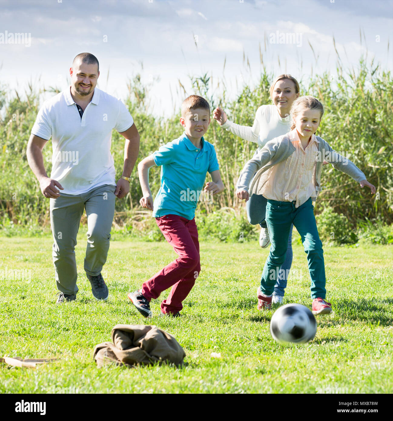 Famille de quatre américains heureux de jouer au football ensemble extérieur Banque D'Images