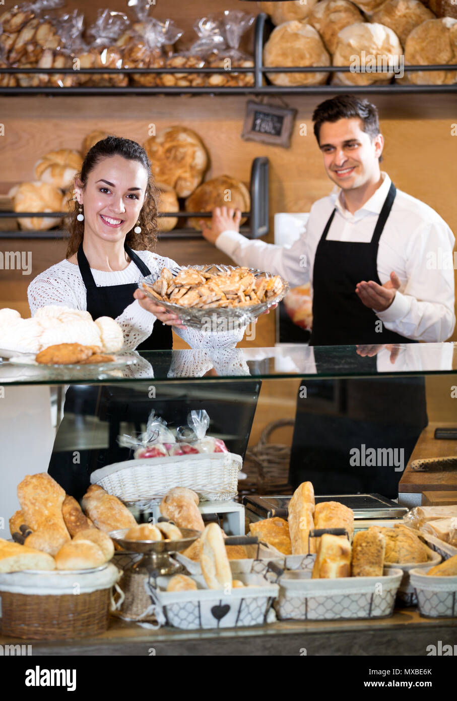 Cheerful young personnel vendeur offrant du pain et pâtisseries différentes à vendre Banque D'Images