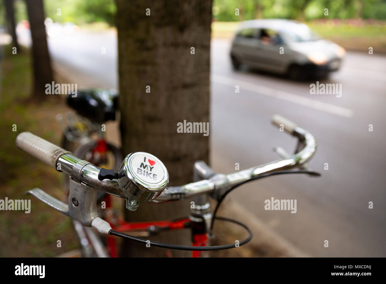 Doublure de bicyclettes un arbre à côté d'une rue de la ville avec une voiture. J'aime mon vélo signe. Banque D'Images