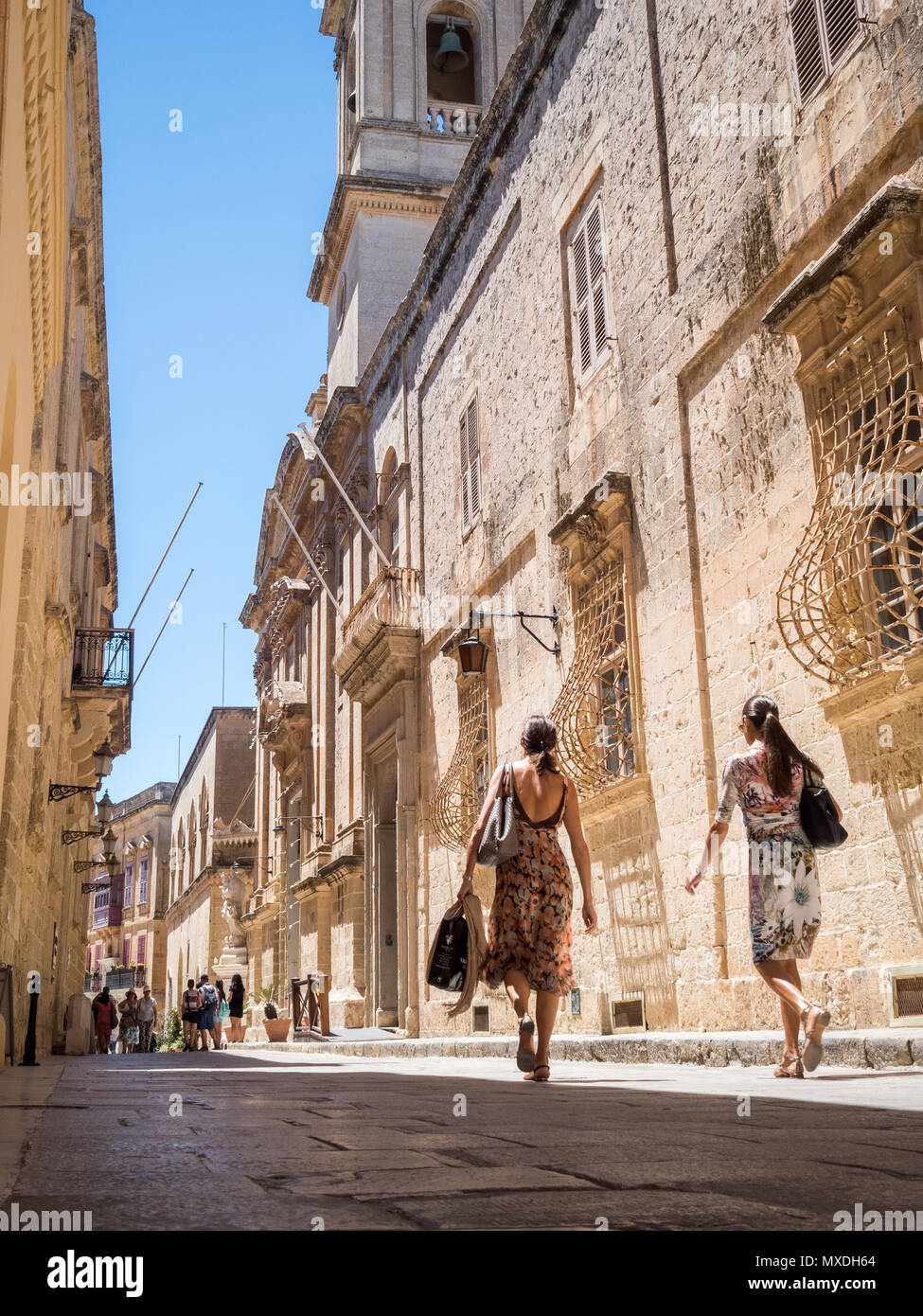 Deux femmes à pied dans une rue étroite à Mdina, l'ancienne capitale de Malte, sous un ciel bleu. Banque D'Images