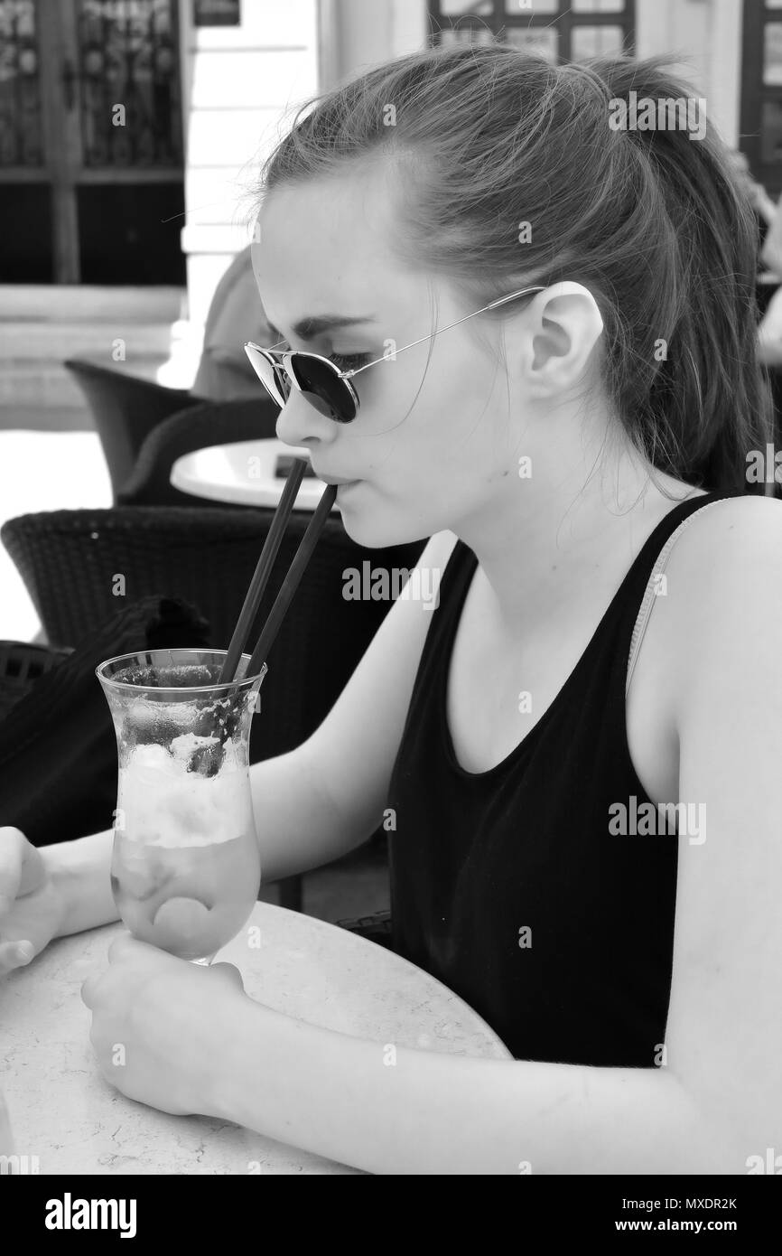 Jeune femme boit un cocktail dans la vieille ville de Rovinj en Croatie Banque D'Images