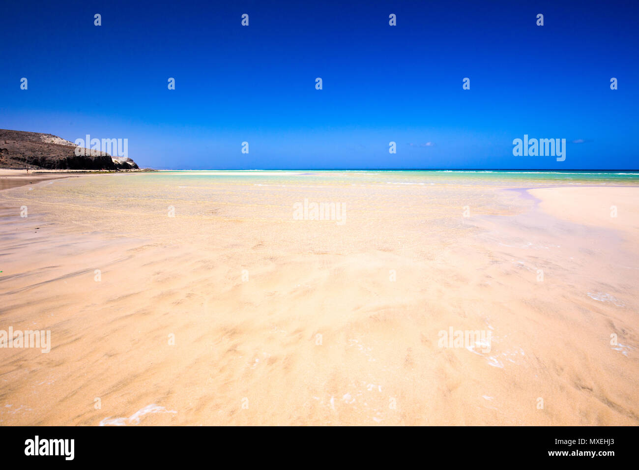 Plage de sable avec la montagne volcanique et green lagoon sur l'île de Fuerteventura, Îles Canaries, Espagne, Europe. Banque D'Images
