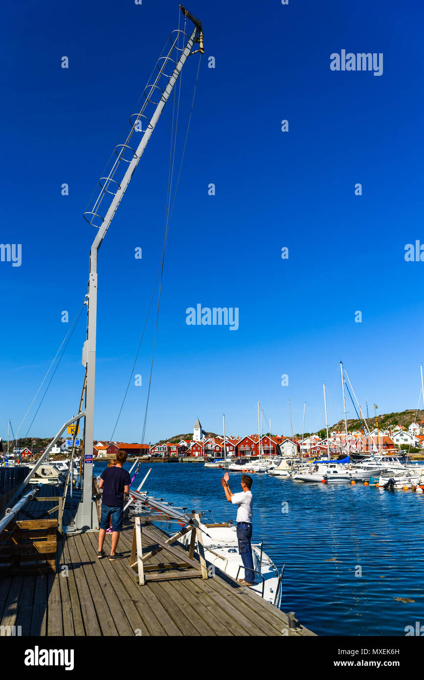 Skarhamn, Tjorn, Suède - Mai 18, 2018 : Documentaire de voyage de la vie quotidienne et le lieu. À l'aide de la famille un boom dans la marina pour élever un voilier duri mât Banque D'Images