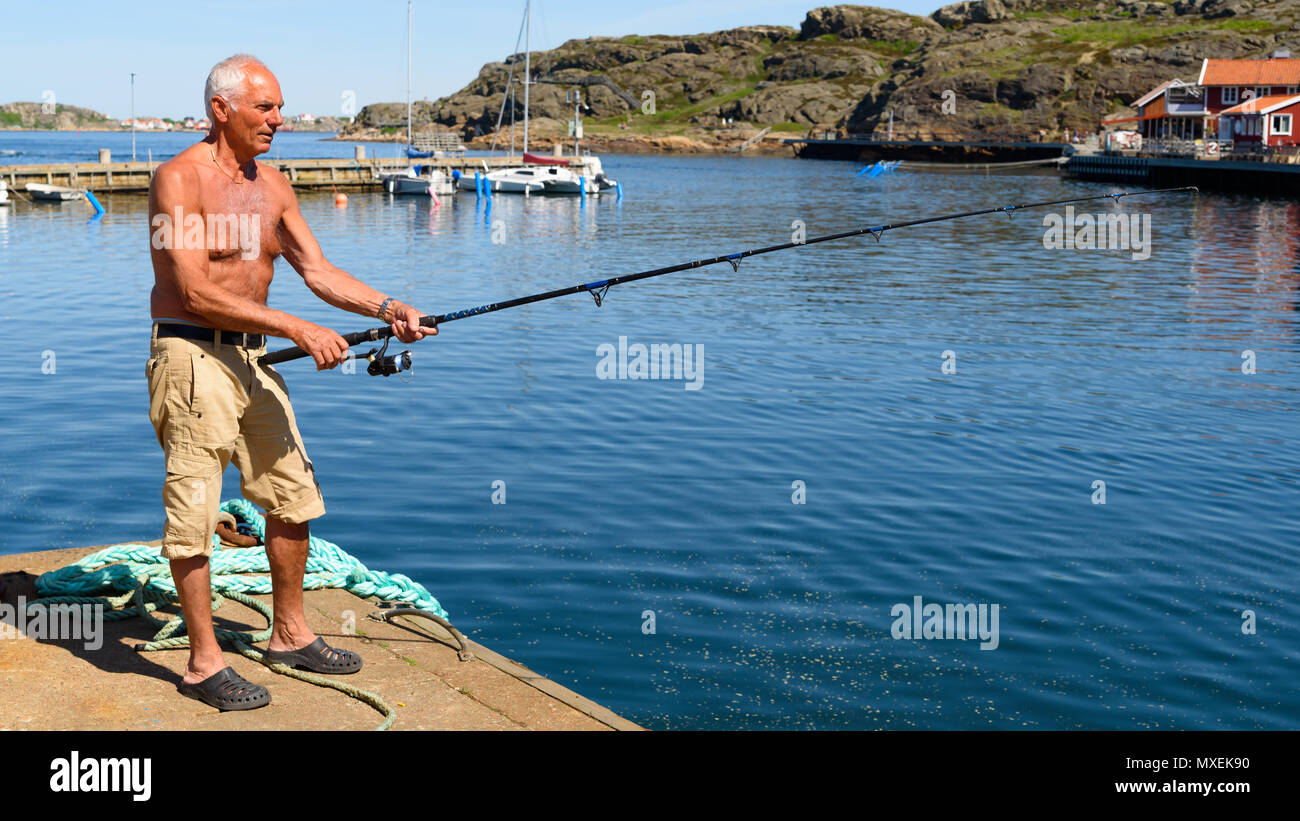 Grundsund, Suède - le 19 mai 2018 : Voyage documentaire de la vie quotidienne et le lieu. Senior male personne debout sur le quai de pêche avec torse nu sur un Banque D'Images