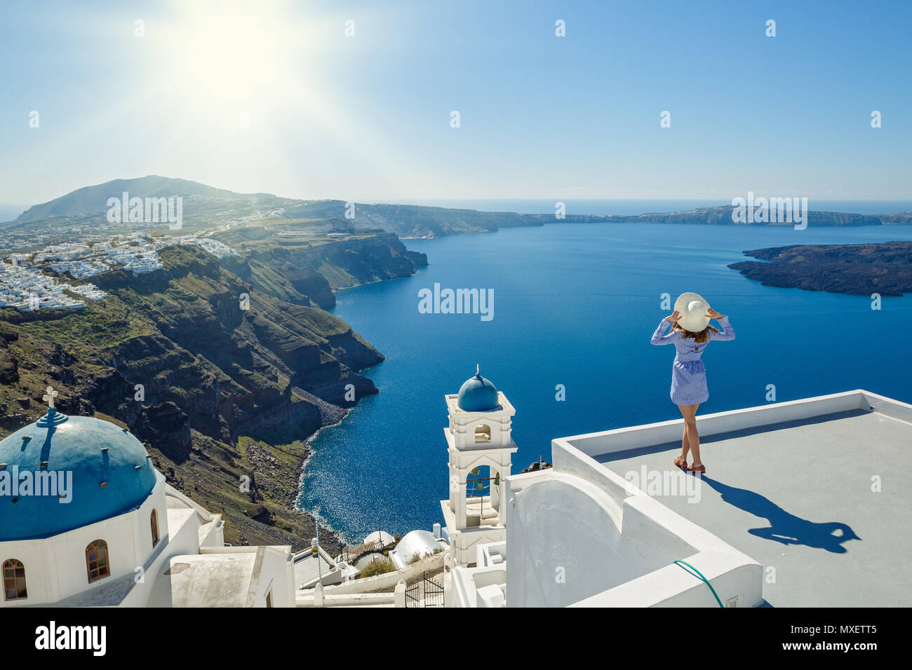 Jeune femme se dresse sur une colline et regarde le paysage marin de Santorini, Grèce Banque D'Images