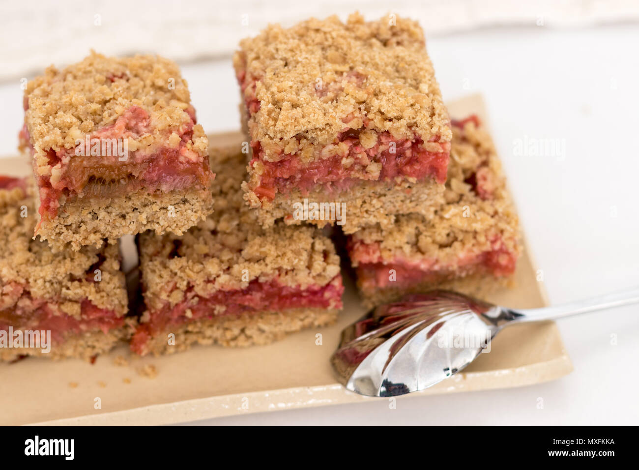 Une collation santé ou un dessert. Crumble aux fraises et rhubarbe bars empilés sur une plaque de céramique faite à la main, avec une cuillère en argent. Banque D'Images