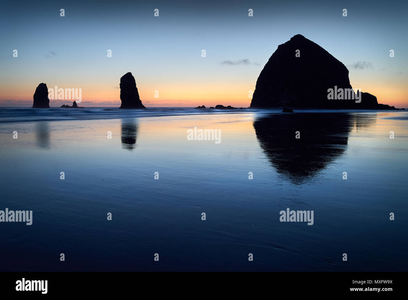 Haystack Rock Sunset, Cannon Beach, Oregon Sunset at Haystack Rock de Cannon Beach, Oregon dans le surf comme échoués sur la plage. United States. Banque D'Images
