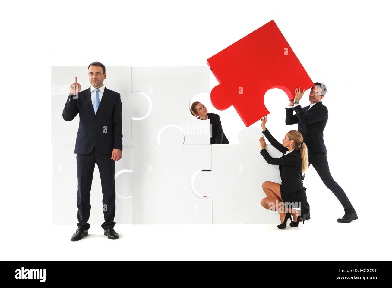 L'équipe d'assemblage grand puzzle et smart businessman standing côté pinting doigt isolé sur fond blanc Banque D'Images