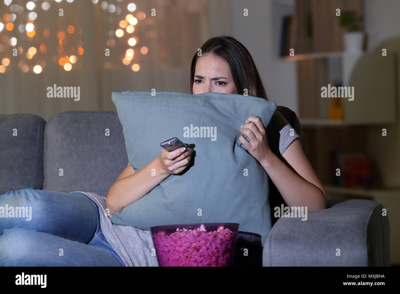 Peur femme regardant la terreur film dans la nuit, assis sur un canapé dans la salle de séjour à la maison Banque D'Images