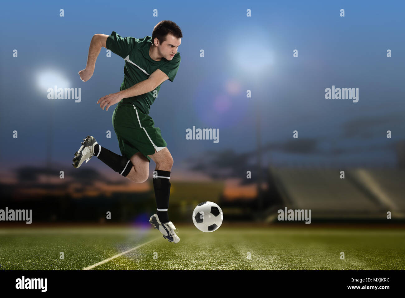 Soccer Player Kicking the ball à l'intérieur d'un stade de football de nuit Banque D'Images