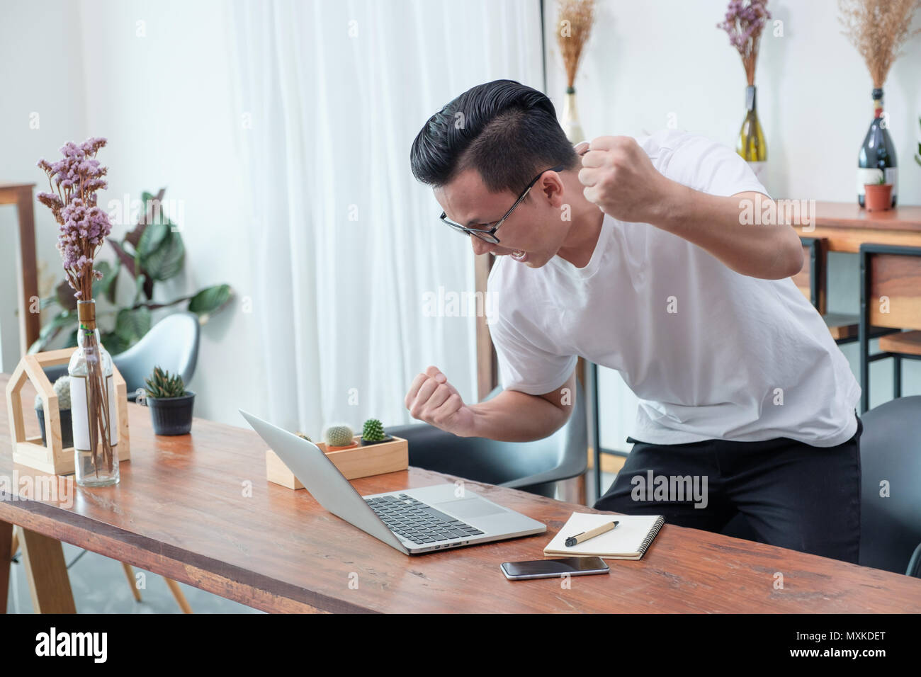 Asian casual man standing jusqu'à bras et célébrer la bonne nouvelle de mobile au coffre à café,succès concept commercial,travailler à l'extérieur, travailler à la maison Banque D'Images