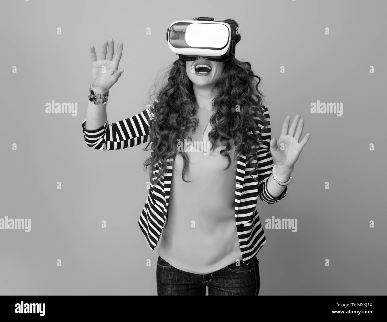 Heureux femme moderne en blouson rayé sur l'arrière-plan à l'aide du casque de réalité virtuelle Banque D'Images