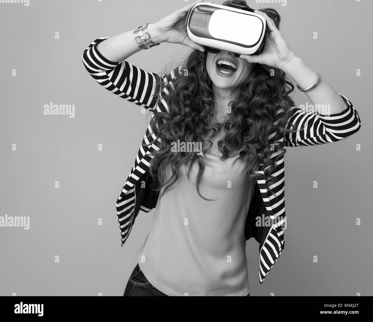 Heureux femme moderne avec de longs cheveux brun ondulé contre arrière-plan à l'aide de VR Banque D'Images