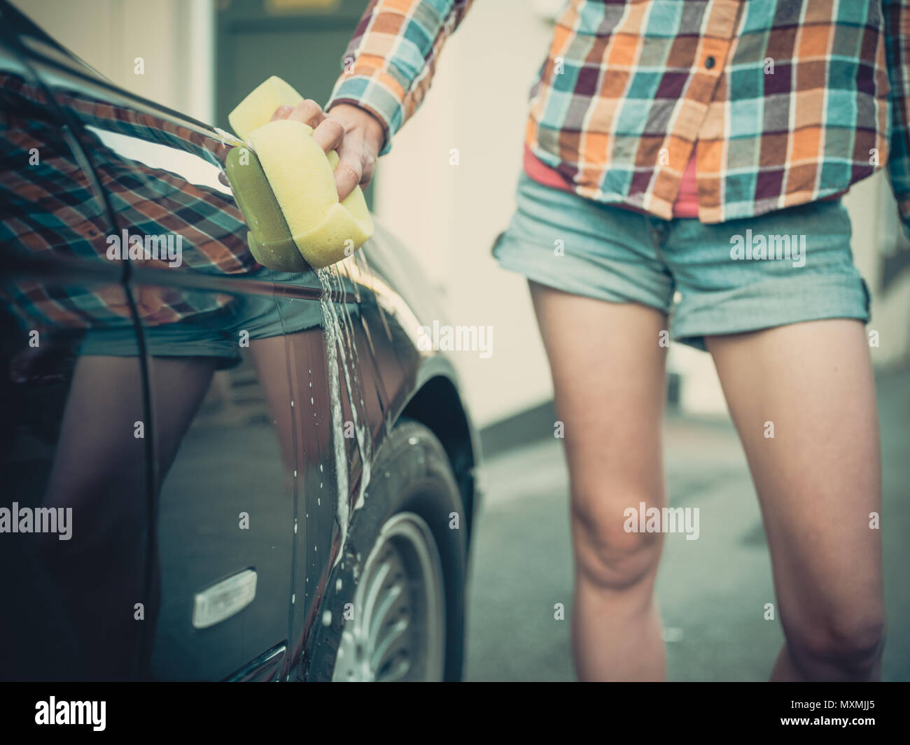 Une jeune femme est savonnage et laver sa voiture Banque D'Images