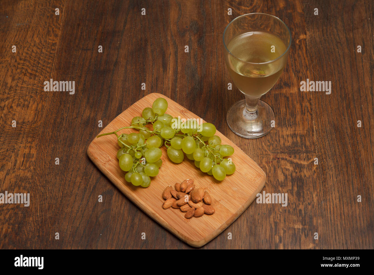 Verre de vin blanc avec un conseil de raisins et noix Banque D'Images