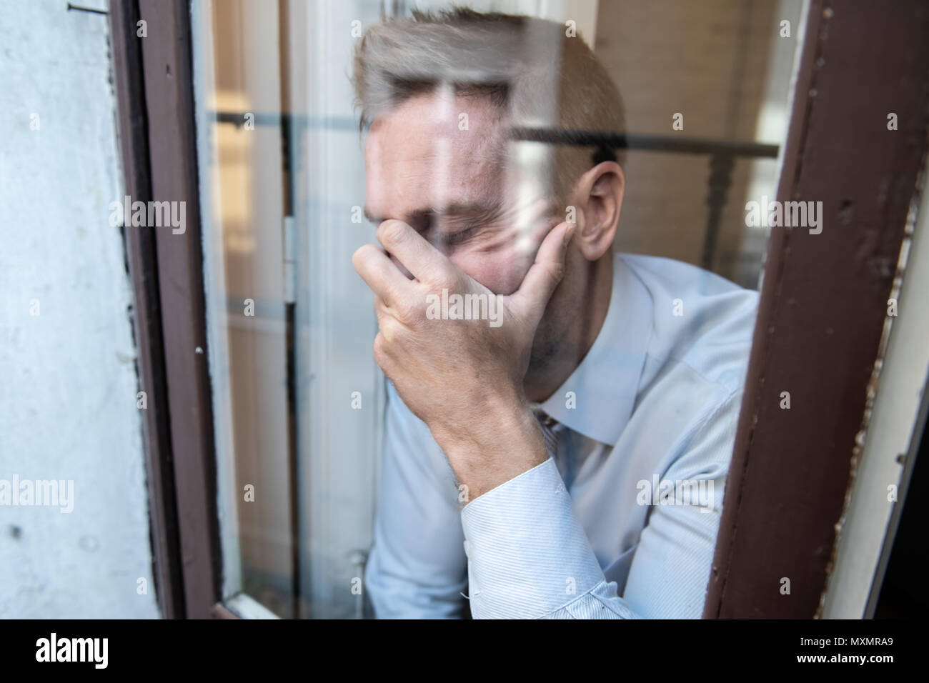 Close up portrait of man triste et déprimé à la réflexion à travers la fenêtre, pensant à sa vie la souffrance mentale dans la dépression il Banque D'Images