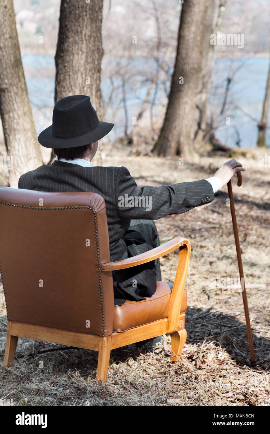 L'homme seul dans la forêt assis sur un fauteuil d'époque, vue arrière Banque D'Images