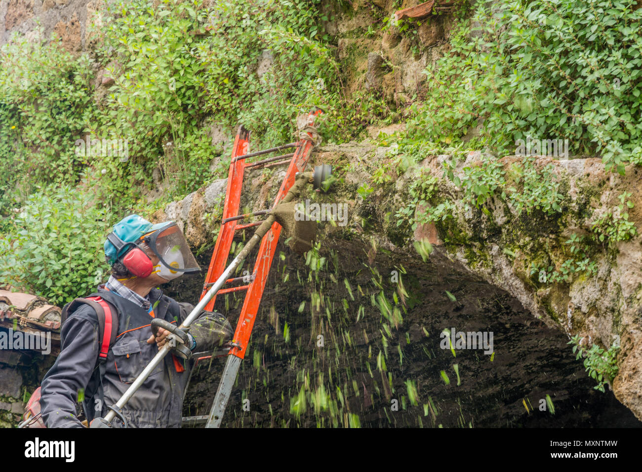 Tuscania (Viterbo), Italie - 2 mai 2018 : l'aide jardinier municipal strimmer dans un site archéologique à Sutri, Italie. Banque D'Images