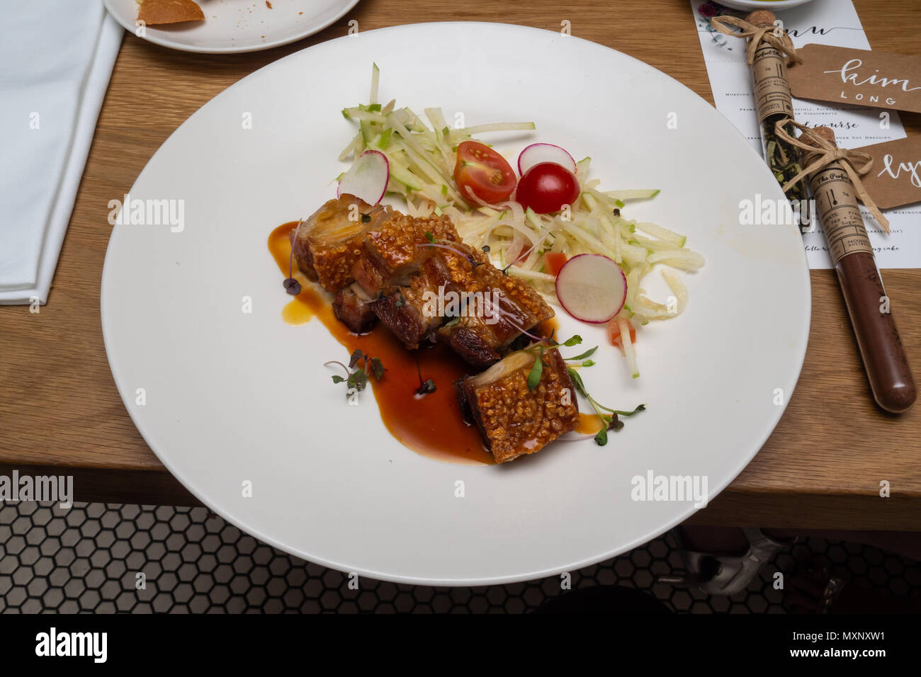 Fine Food : rôti de porc croustillant avec une salade de tomates cerise et pomme radis rouge Banque D'Images