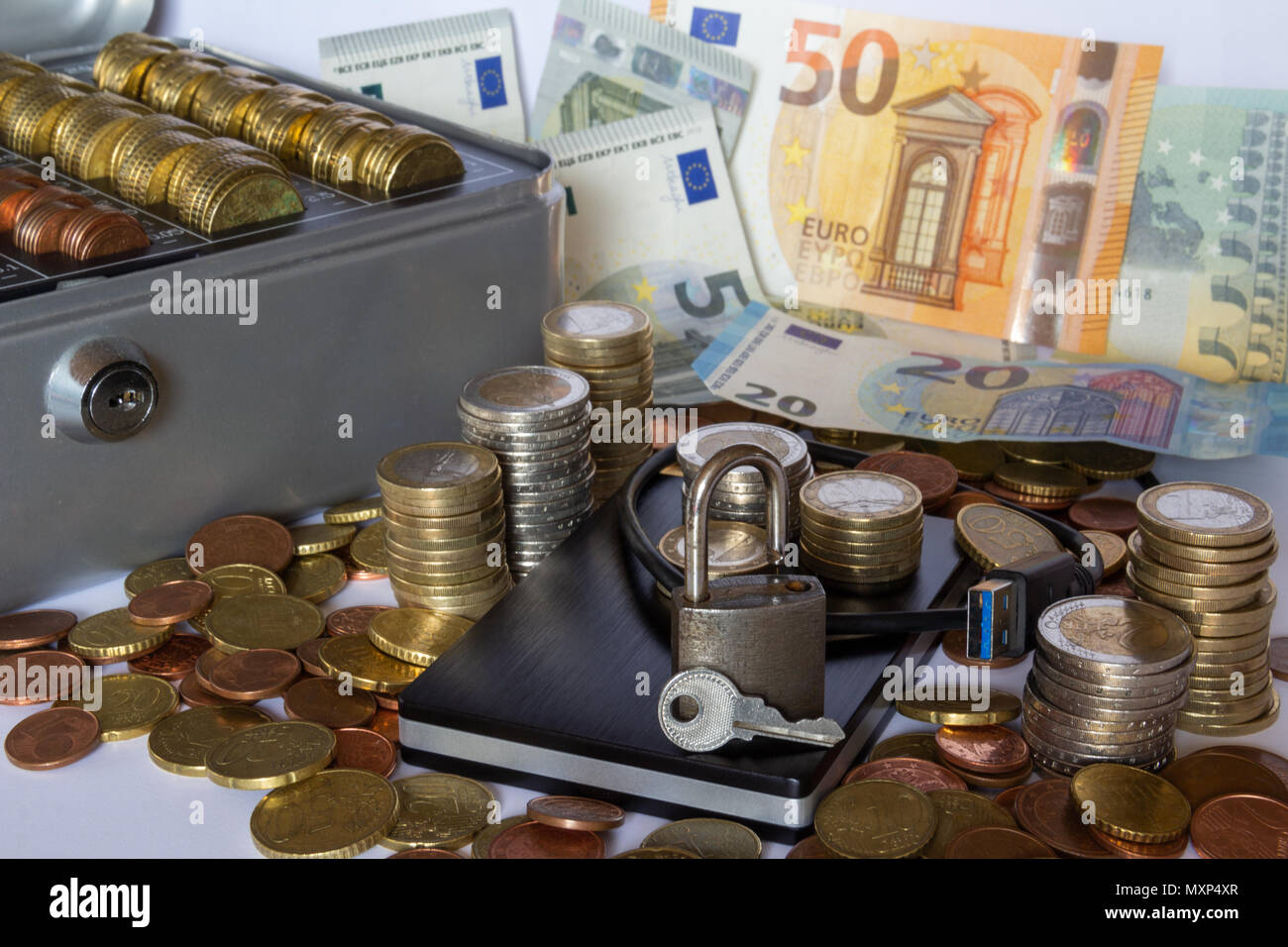 Argent empilés autour d'un disque dur externe avec billets dans l'arrière-plan Banque D'Images