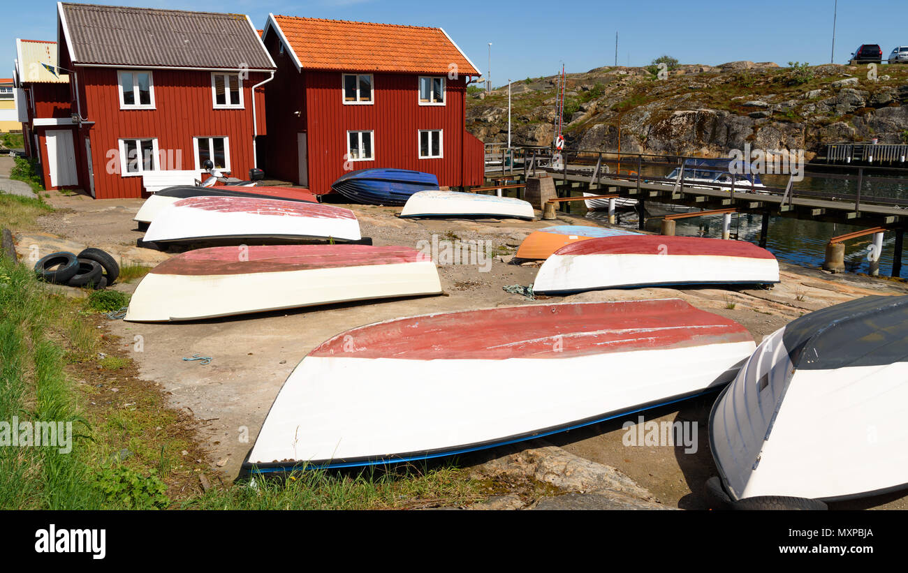 L'envers des bateaux sur terre dans une zone du port et cabines en bois rouge en arrière-plan. Smogen sur la côte occidentale de la Suède. Banque D'Images