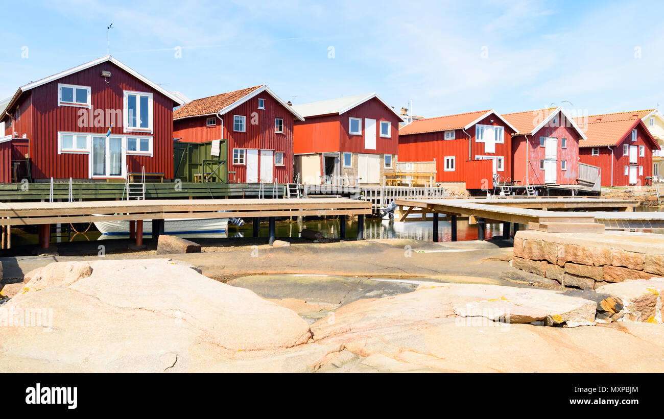 Les hangars à bateaux en bois rouge sur une journée ensoleillée à Smogen sur la côte occidentale de la Suède. Banque D'Images