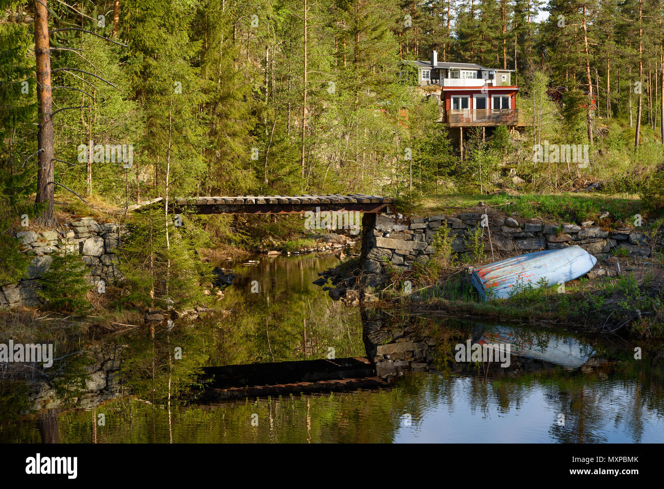 Petit pont sur une petite rivière avec une barque à l'envers à côté. Forêt et d'une maison dans l'arrière-plan. Elgsjo en dehors de Notodden, la Norvège. Banque D'Images