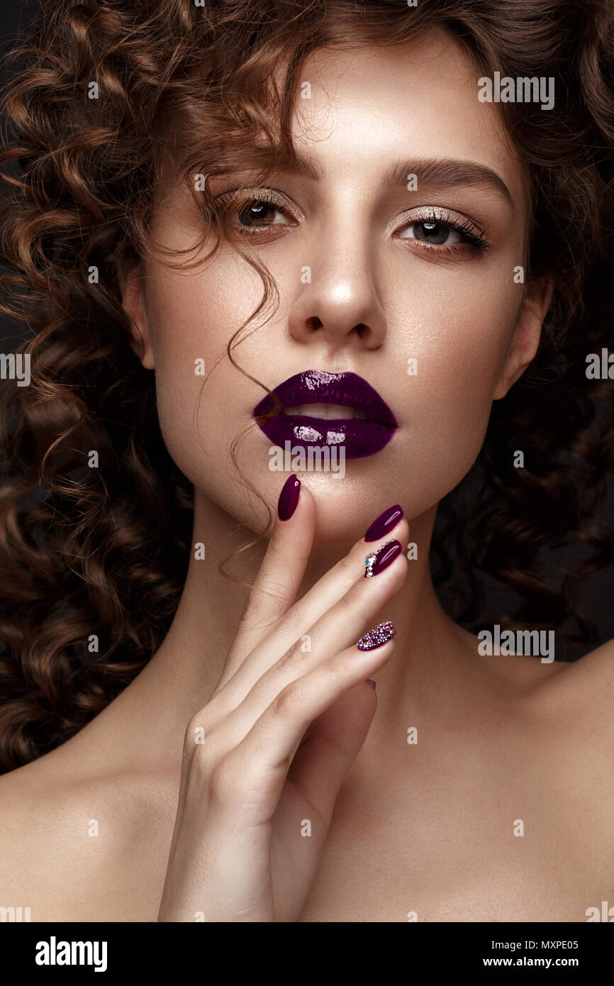 Belle fille avec soir maquillage, lèvres pourpres, boucles et clous. manucure design beauté visage. Banque D'Images