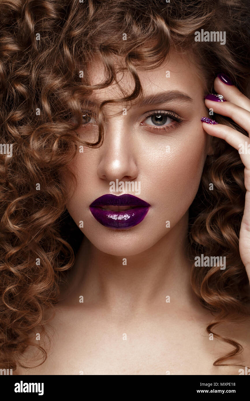 Belle fille avec soir maquillage, lèvres pourpres, boucles et clous. manucure design beauté visage. Banque D'Images