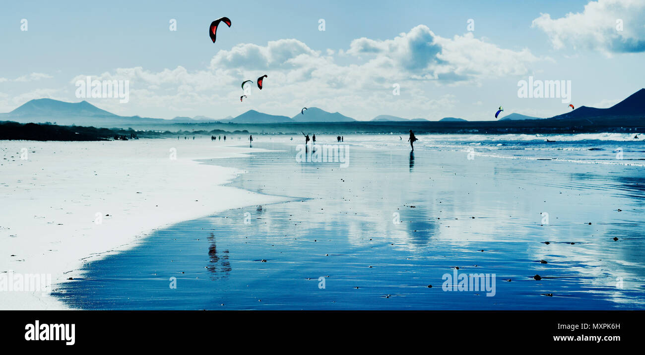 Une vue panoramique de la plage de Famara Lanzarote, Canaries, Espagne, avec certains nageurs méconnaissable et kitesurfers en arrière-plan, dans le dos Banque D'Images