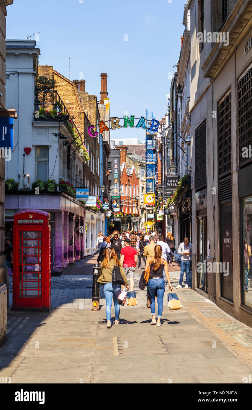 Inscrivez-colorées brillantes à l'entrée et clients dans la célèbre zone piétonne Carnaby Street dans le West End, Soho, London W1 sur une journée ensoleillée Banque D'Images