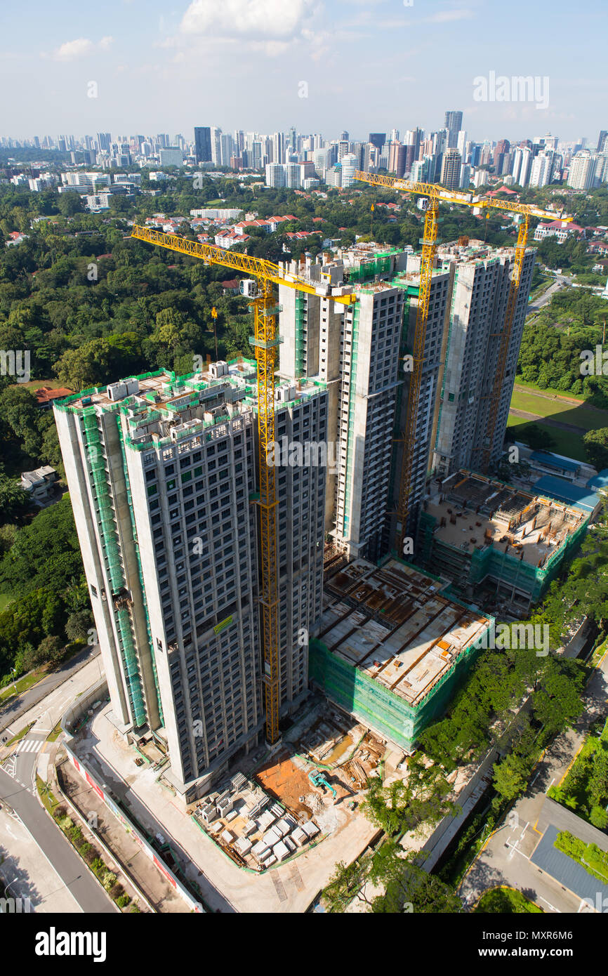 Vue verticale de trois grues à tour impliquées dans la construction d'appartements à Singapour. Banque D'Images