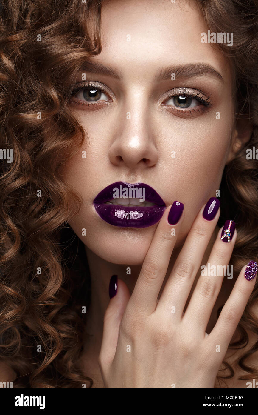 Belle fille avec soir maquillage, lèvres pourpres, boucles et clous. manucure design beauté visage. Banque D'Images