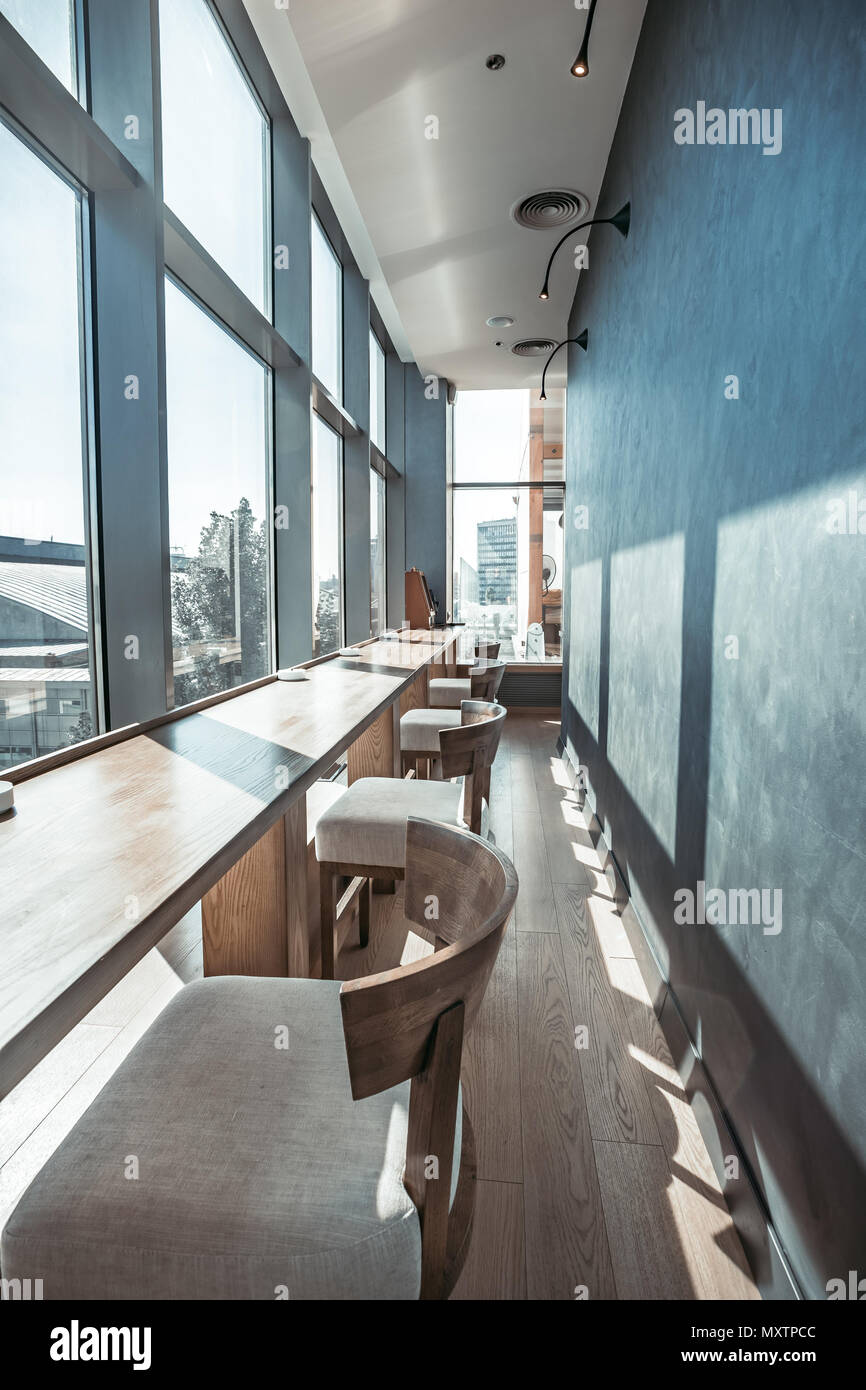 De l'intérieur confortable du restaurant moderne. La partie interne de la  salle principale avec la rangée de chaises de bar et table long bar en face  de la fenêtre de verre transparent.